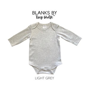 K&ouml;nnte beinhalten: Hellgrauer lang&auml;rmliger Baby-Body mit Rundhalsausschnitt und Druckkn&ouml;pfen. Der Body ist von Blanks by Tiny Wolfe.