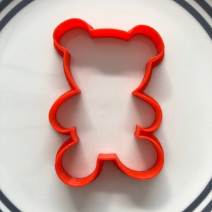May include: Orange plastic cookie cutter shaped like a bear.