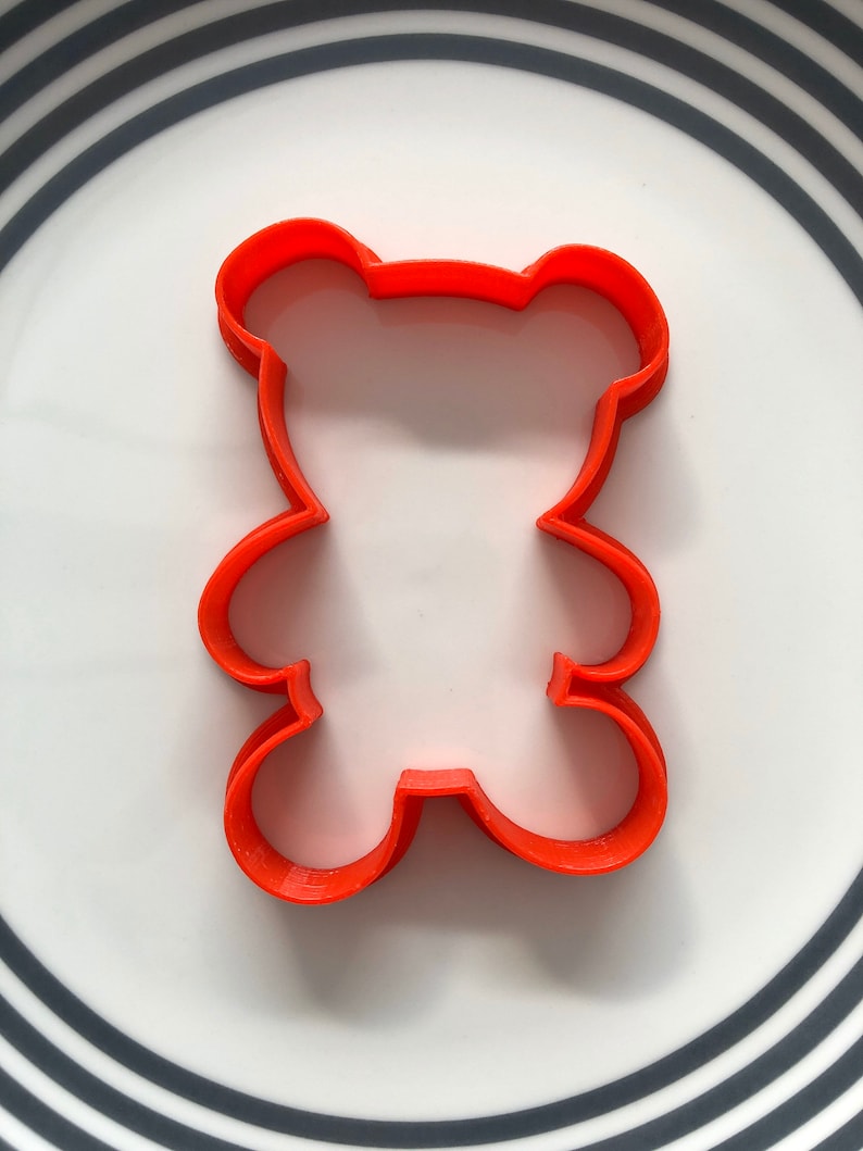 May include: Orange plastic cookie cutter shaped like a bear.
