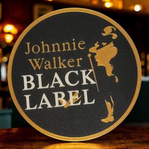 K&ouml;nnte beinhalten: Runder, schwarzer Untersetzer mit goldenem Rand. Der Untersetzer zeigt den Text "Johnnie Walker BLACK LABEL" in Wei&szlig; und Gold. Eine goldene Silhouette des Johnnie Walker Striding Man ist ebenfalls zu sehen.
