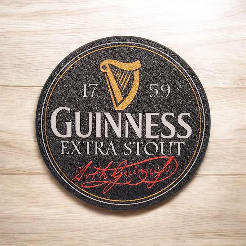 K&ouml;nnte beinhalten: Ein runder, schwarzer Guinness Extra Stout Untersetzer mit einem goldenen Harfenlogo, den Zahlen 17 und 59 und der Unterschrift "Arth Guinness" in roter Schrift. Der Untersetzer hat eine strukturierte Oberfl&auml;che und einen goldenen Rand.