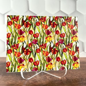 May include: A rectangular decorative panel featuring a stained-glass design of red and yellow tulips with green stems and leaves. The panel is supported by a white metal stand, set against a white geometric background.