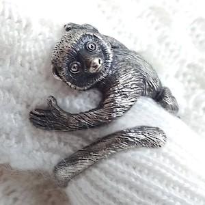 Könnte beinhalten: Ein silberner Ring mit einer detaillierten Skulptur eines Affen, dessen Schwanz um das Band gewickelt ist.