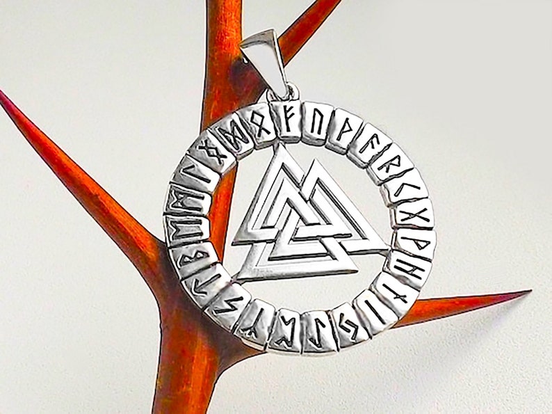 May include: Silver pendant featuring a circular design with the Norse symbol Vegvisir in the center. The circle is made up of runes, the ancient alphabet of the Germanic peoples.