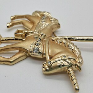 以下が含まれることがあります： 透明なラインストーンのアクセントが付いた、金色のメリーゴーランドの馬のブローチ。 ヴィンテージスタイルのピンは、なびくたてがみと装飾的なサドルを備えた馬の詳細なデザインが特徴です。 ブローチはクラシックなアクセサリーです。