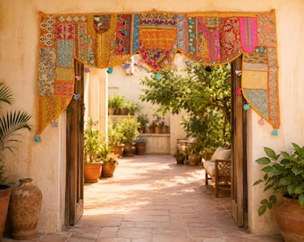 Könnte beinhalten: Ein dekorativer Türbehang aus Stoff mit einem lebendigen Patchwork aus bestickten Textilien in Orange-, Gelb-, Rosa- und Blautönen. Der Behang hat einen gewellten unteren Rand, der mit kleinen, bunten hängenden Quasten und Stoffbommeln verziert ist.