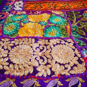 May include: A colorful patchwork quilt with intricate embroidery and sequins. The quilt is made of various fabrics in shades of purple, green, yellow, orange, and red. The quilt is decorated with floral patterns and beaded accents.