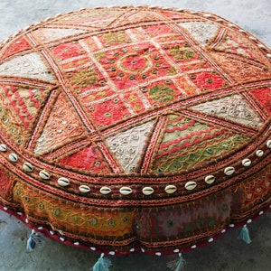 May include: A round, multi-colored floor cushion with a patchwork design. The cushion is made of fabric and has a decorative border of white shells.
