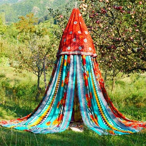 May include: A conical fabric canopy featuring a vibrant red top section with small circular embellishments, transitioning into a multi-colored lower section with turquoise, orange, and yellow panels decorated with floral and geometric patterns.