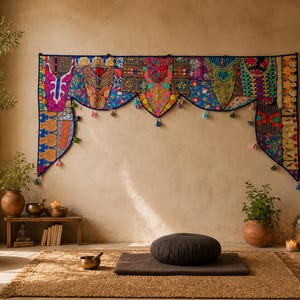 May include: A wide, rectangular wall hanging featuring a vibrant patchwork of colourful embroidered fabrics in shades of blue, pink, orange, and green. The piece has a scalloped bottom edge adorned with small, dangling tassels and decorative trim.