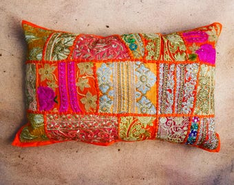 May include: A colorful patchwork pillow with a mix of orange, pink, yellow, and green fabrics. The pillow is decorated with intricate embroidery and sequins.
