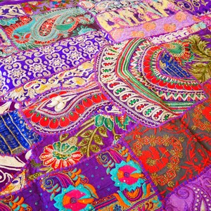 May include: A colorful patchwork quilt with a variety of floral and geometric patterns in shades of purple, red, green, and blue. The quilt is made of different fabrics and textures, and it has a unique and bohemian style.