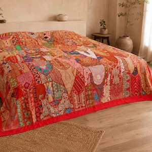 Puede incluir: Una colcha grande que presenta un diseño de patchwork vibrante con varios paneles de tela en tonos rojos, naranjas y multicolores. El tejido muestra bordados intrincados, patrones detallados y costuras decorativas, con un borde rojo sólido.