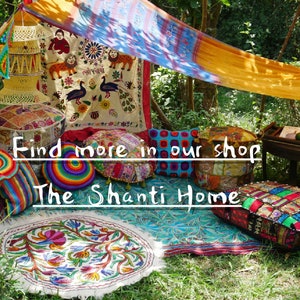 May include: A display of colorful, handcrafted home decor items. The scene includes round and square floor cushions, a decorative tapestry with peacocks, and a variety of other textiles. The text "Find more in our shop The Shanti Home" is visible.