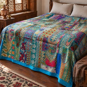 May include: A patchwork bedspread featuring a vibrant array of multicoloured fabric panels with intricate embroidery, metallic thread accents, and floral patterns, finished with a solid bright blue border along the bottom edge.