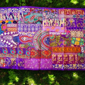 May include: A purple patchwork tapestry with intricate embroidery in various colors, including gold, red, and blue. The tapestry is made of different fabrics and textures, creating a unique and vibrant design.