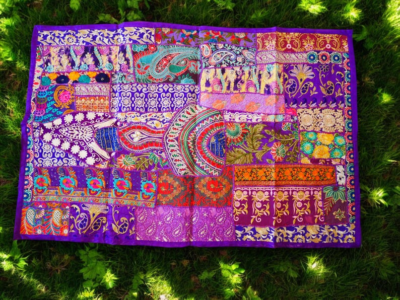 May include: A purple patchwork tapestry with intricate embroidery in various colors, including gold, red, and blue. The tapestry is made of different fabrics and textures, creating a unique and vibrant design.