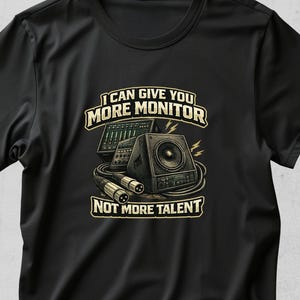 Pode incluir: Camiseta preta com um design gráfico com equipamentos de áudio, incluindo um alto-falante, uma mesa de mistura e cabos. O texto diz "I CAN GIVE YOU MORE MONITOR NOT MORE TALENT."