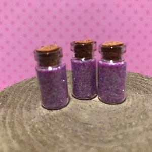May include: Three small glass jars with cork lids filled with purple glitter.