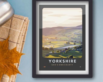 May include: A framed print with a scenic landscape view of a valley with rolling hills and a river winding through it. The print has the text "Yorkshire, God's Own County" at the bottom.