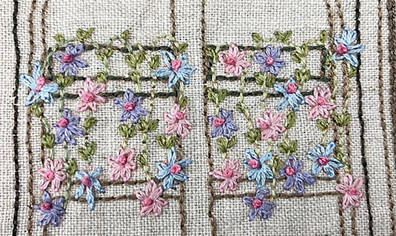 Puede incluir: Primer plano de un dise&ntilde;o floral bordado. El dise&ntilde;o presenta flores rosas, azules y moradas con hojas verdes, dispuestas en un patr&oacute;n de enrejado. El fondo es una tela beige claro con rayas verticales marrones.
