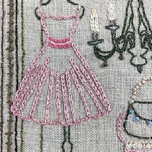 Puede incluir: Arte textil bordado con un vestido rosa en una percha, una l&aacute;mpara de ara&ntilde;a y una silla. El vestido est&aacute; detallado con costuras rosas. La l&aacute;mpara de ara&ntilde;a y la silla son de color verde oscuro y beige. El fondo es una tela texturizada y neutra.