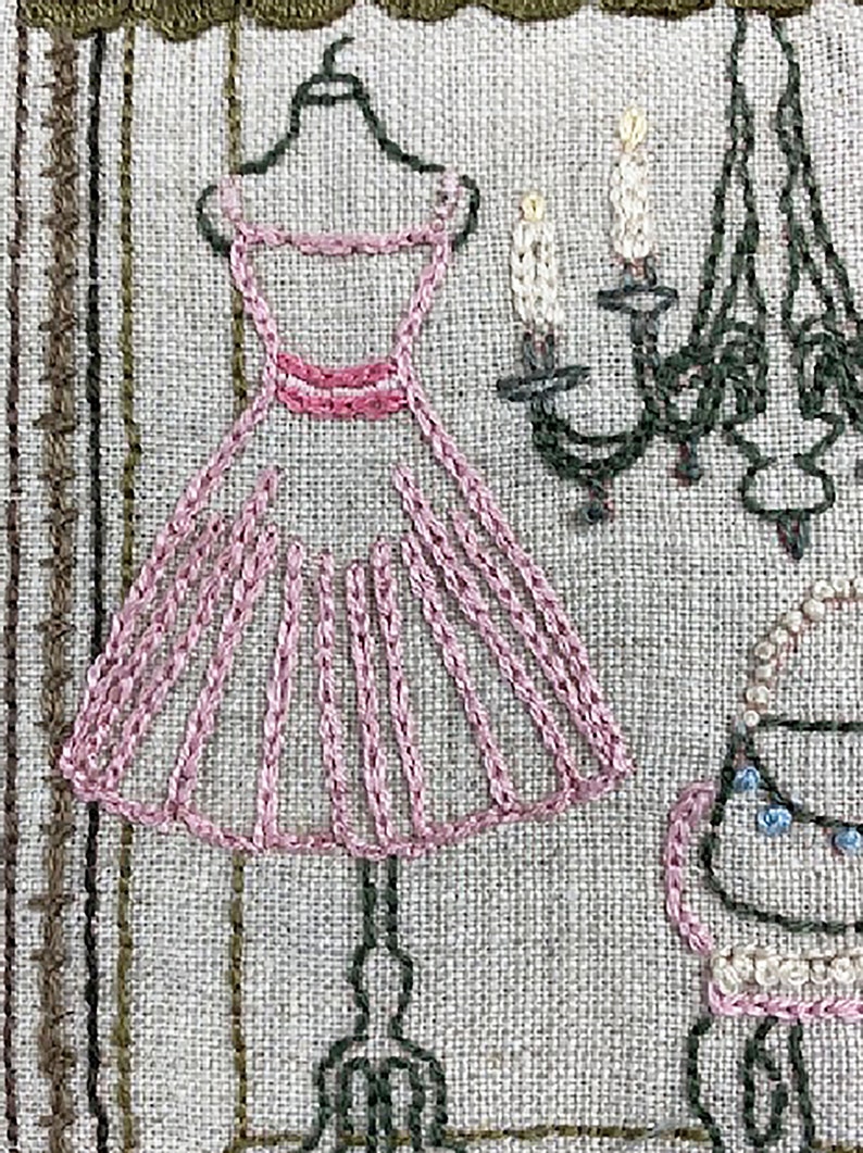 Puede incluir: Arte textil bordado con un vestido rosa en una percha, una l&aacute;mpara de ara&ntilde;a y una silla. El vestido est&aacute; detallado con costuras rosas. La l&aacute;mpara de ara&ntilde;a y la silla son de color verde oscuro y beige. El fondo es una tela texturizada y neutra.