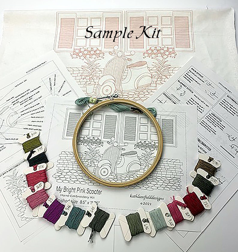 Puede incluir: Un kit de bordado con el texto "Sample Kit" y "My Bright Pink Scooter". El kit incluye un bastidor de bordado de madera, hilo de bordar de varios colores e instrucciones impresas. El dise&ntilde;o presenta un scooter y elementos arquitect&oacute;nicos.