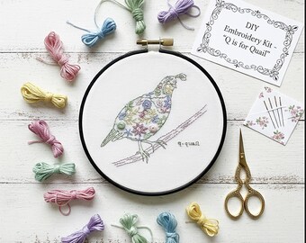 May include: A DIY embroidery kit featuring a colorful embroidered quail on a branch, surrounded by colorful embroidery floss, needles, and gold scissors. The kit includes the text "DIY Embroidery Kit - 'Q is for Quail'".