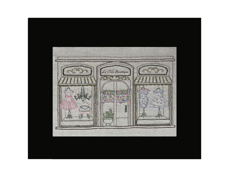 Puede incluir: Imagen bordada de un escaparate de boutique con el texto "Le Chic Boutique". La tienda presenta tres escaparates con vestidos en maniqu&iacute;es, una l&aacute;mpara de ara&ntilde;a y detalles florales. La paleta de colores incluye rosa, azul y verde sobre un fondo neutro.