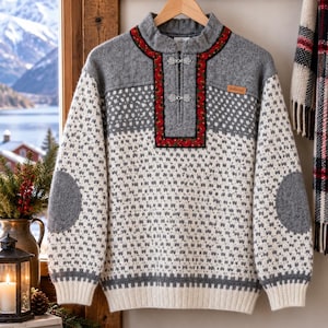 May include: A gray and white knit sweater featuring a high collar with a half-zip closure, two silver-toned metal clasps, and a red floral trim. The garment includes solid gray elbow patches, a ribbed hem, and a small brown rectangular brand label.