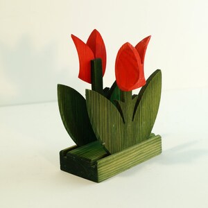 May include: Wooden napkin holder shaped like a bouquet of red tulips with green leaves.