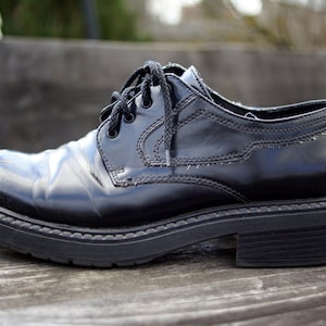 Op de afbeelding: Zwarte leren veterschoenen met een dikke, gestructureerde zool. De schoenen hebben een gepolijste afwerking en een licht puntige neus.