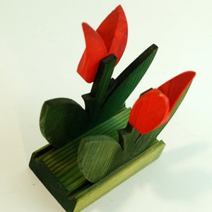 May include: Wooden napkin holder shaped like a bouquet of red tulips with green leaves.