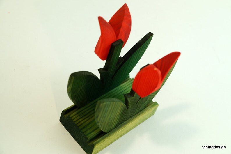 May include: Wooden napkin holder shaped like a bouquet of red tulips with green leaves.