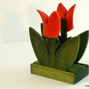May include: A wooden napkin holder shaped like a bouquet of red tulips with green leaves. The holder is made of wood and has a rustic, vintage look.