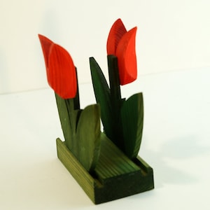 May include: Wooden napkin holder shaped like a bouquet of red tulips with green leaves.