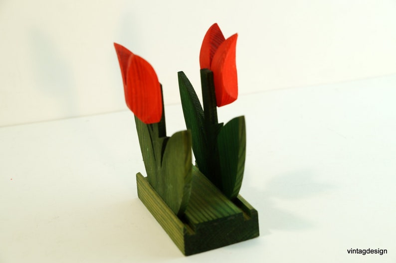 May include: Wooden napkin holder shaped like a bouquet of red tulips with green leaves.