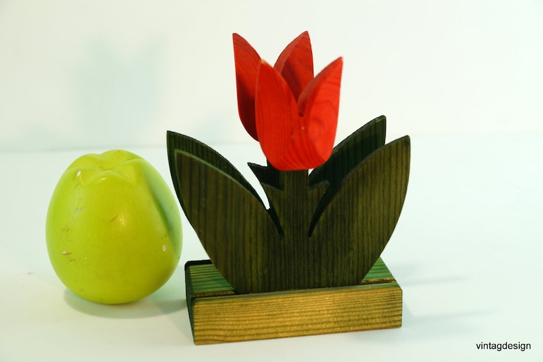 May include: Wooden napkin holder shaped like a red tulip with green leaves and a brown base.