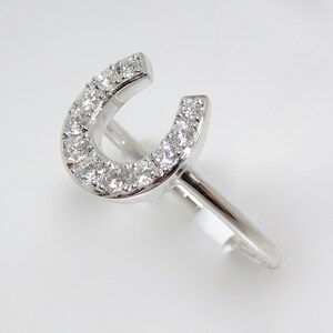 May include: A silver ring with a horseshoe design set with small diamonds.