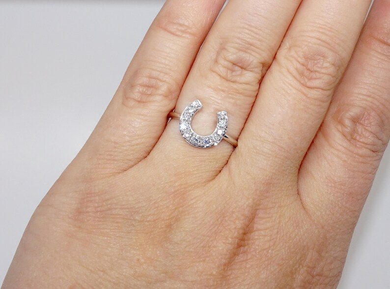May include: A silver ring with a horseshoe design set with small clear stones.