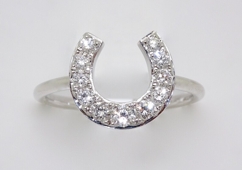 May include: A silver ring with a horseshoe design set with small clear diamonds.