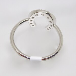 May include: A silver ring with a horseshoe design set with small clear stones.