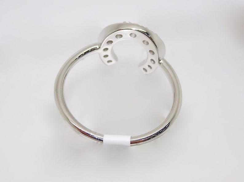 May include: A silver ring with a horseshoe design set with small clear stones.