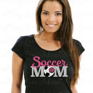 May include: A black t-shirt with the text "Soccer Mom" in pink and gray lettering. A soccer ball with a pink heart and monogram is in the center of the text.