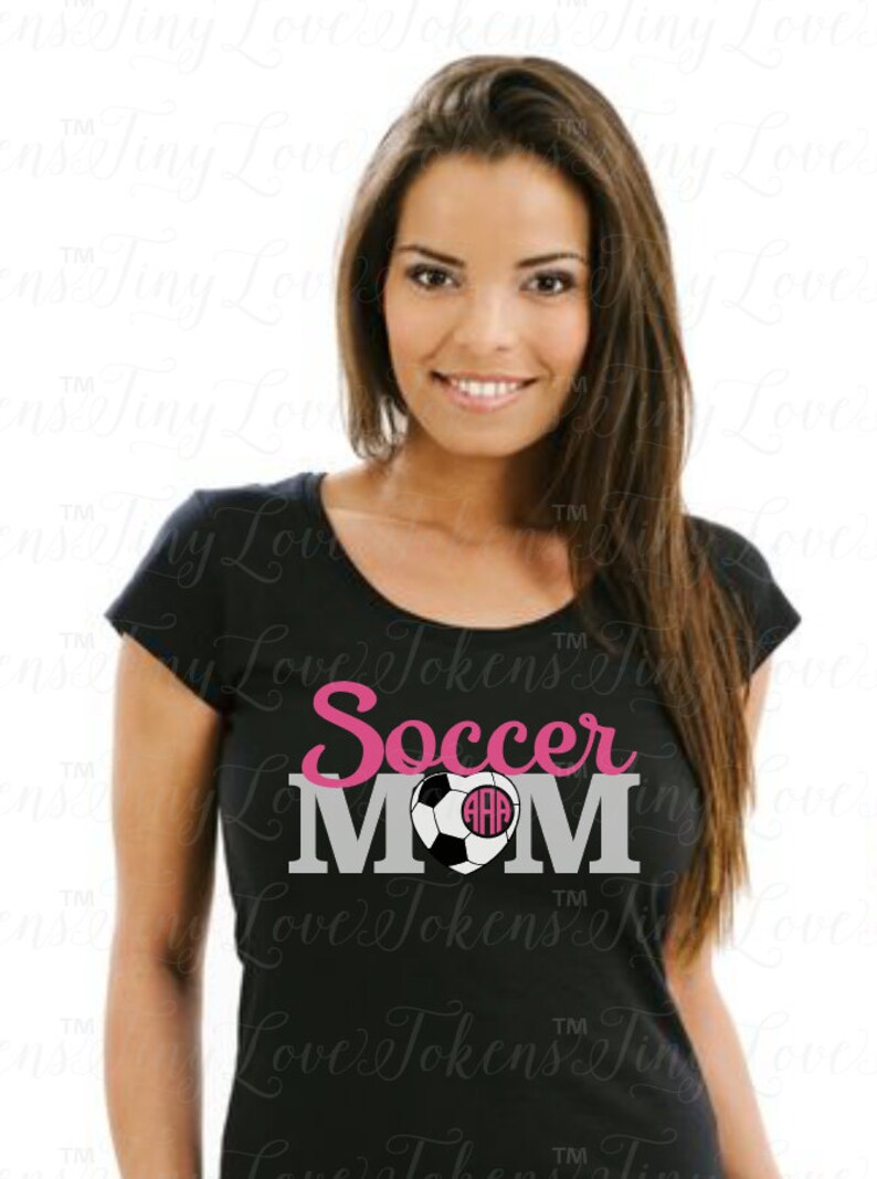May include: A black t-shirt with the text "Soccer Mom" in pink and gray lettering. A soccer ball with a pink heart and monogram is in the center of the text.
