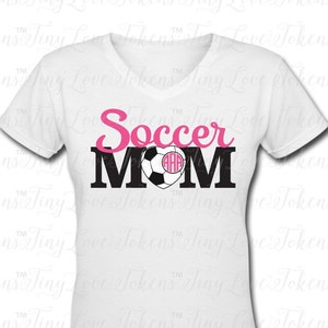 May include: White t-shirt with a pink and black design that says "Soccer Mom" with a soccer ball and a monogram in the heart.