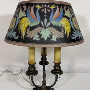 May include: A white ceramic mug with a black handle and the text "But First, Coffee" in a bold, black font. The mug is set against a blurred background, suggesting a cozy setting.