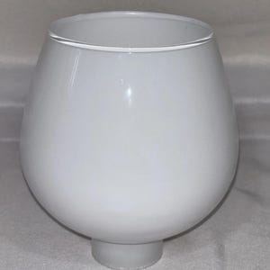 May include: A white, opaque glass lampshade with a rounded, bulbous shape. The lampshade has a wide opening at the top and a short, cylindrical base. The overall design is simple and modern.