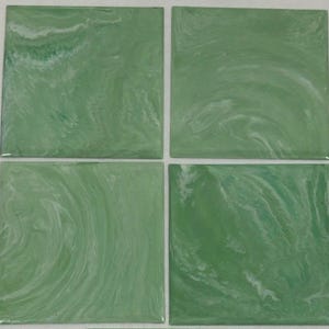 May include: Four square green tiles with a marbled white pattern. The tiles are arranged in a square formation. The green color has a slight variation in shade, and the white pattern creates a swirling effect.